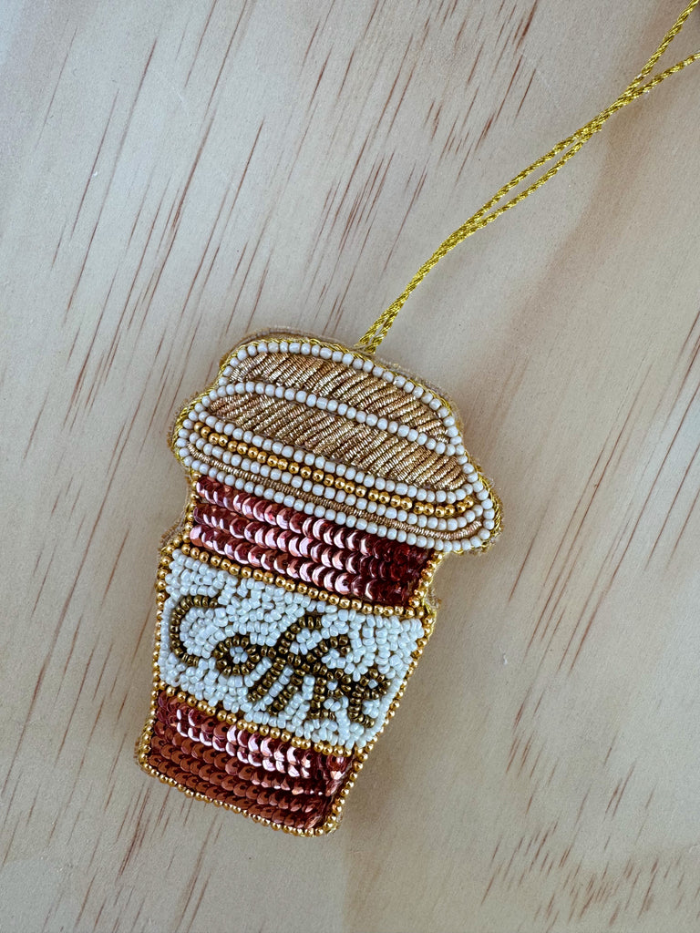 Beaded coffee cup ornament on a wooden surface