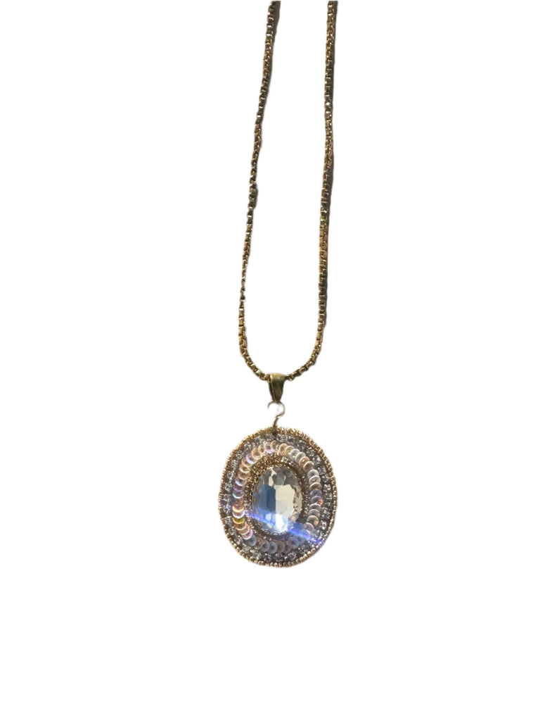 Gold necklace with a circular pendant on a wooden surface