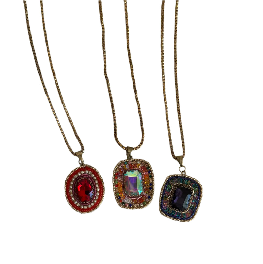 Three necklaces with colorful pendants on a white background