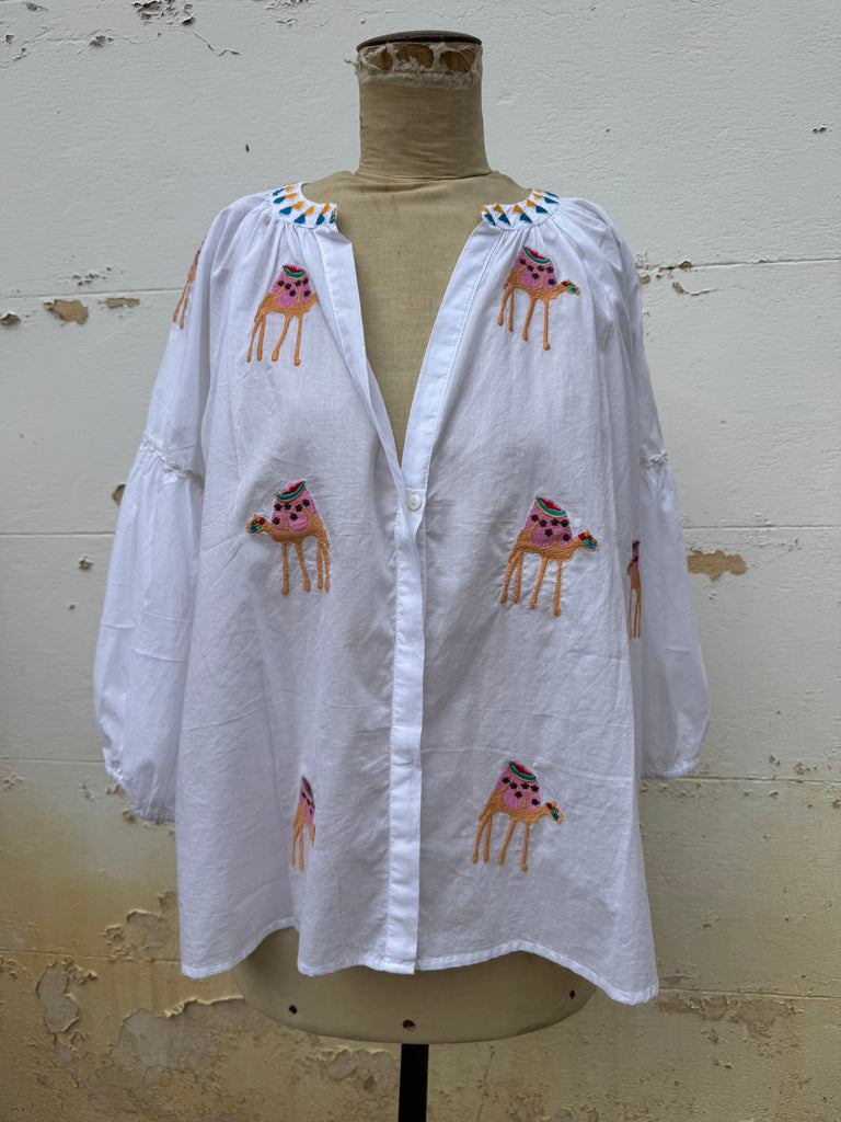 White garment with embroidered designs on a mannequin against a plain background