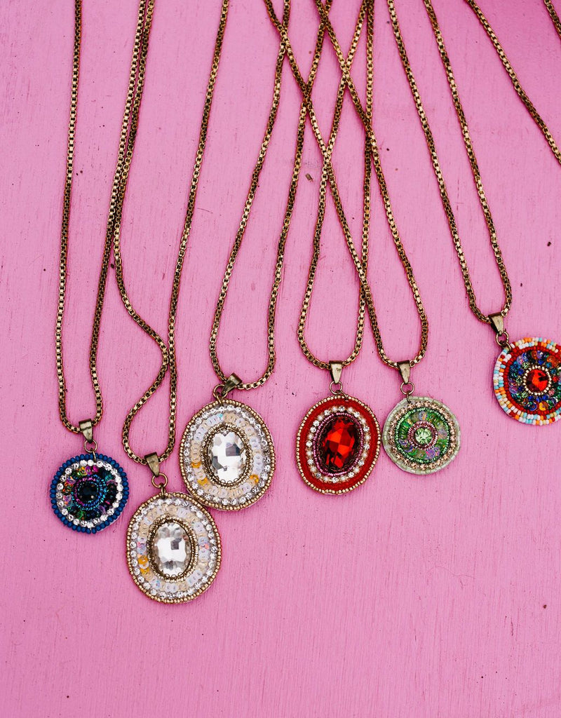 Necklaces with colorful pendant stones on a pink background