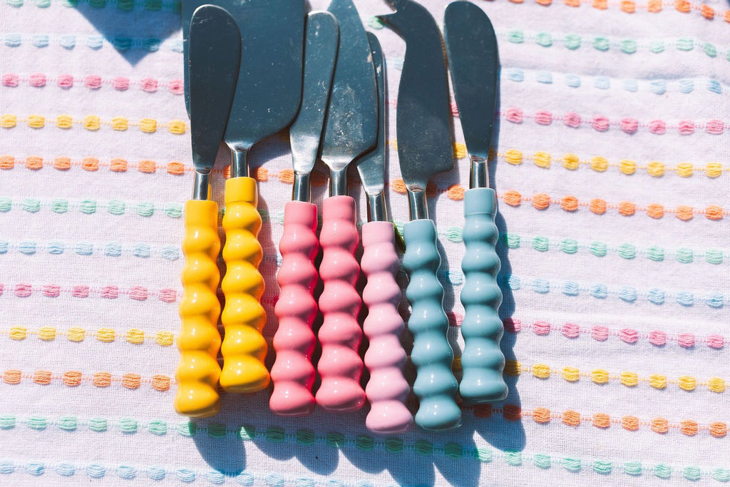 Set of colorful cake knives on a patterned surface