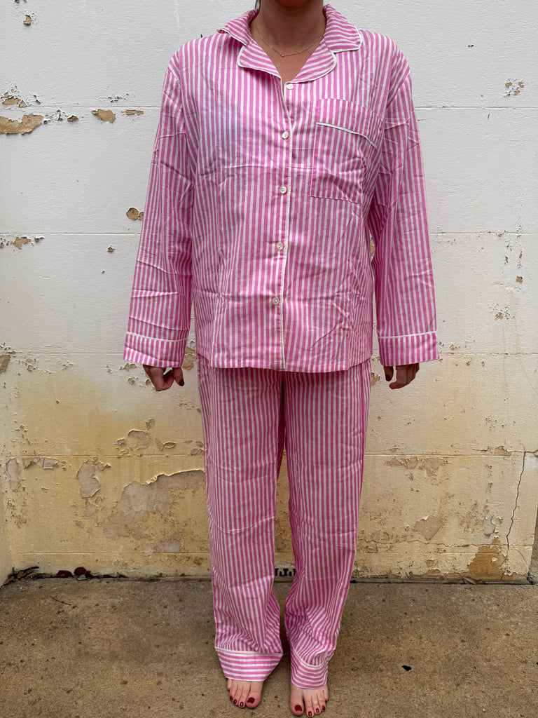 Person wearing pink and white striped pajamas on a textured floor.