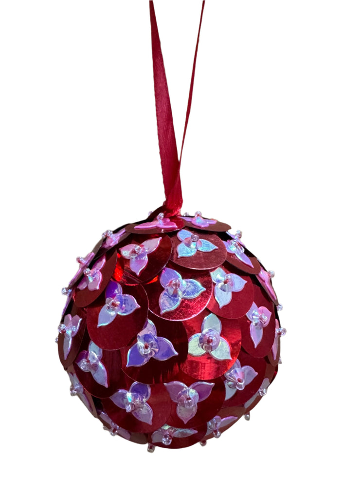 Decorative red ball ornament with floral patterns on a wooden surface