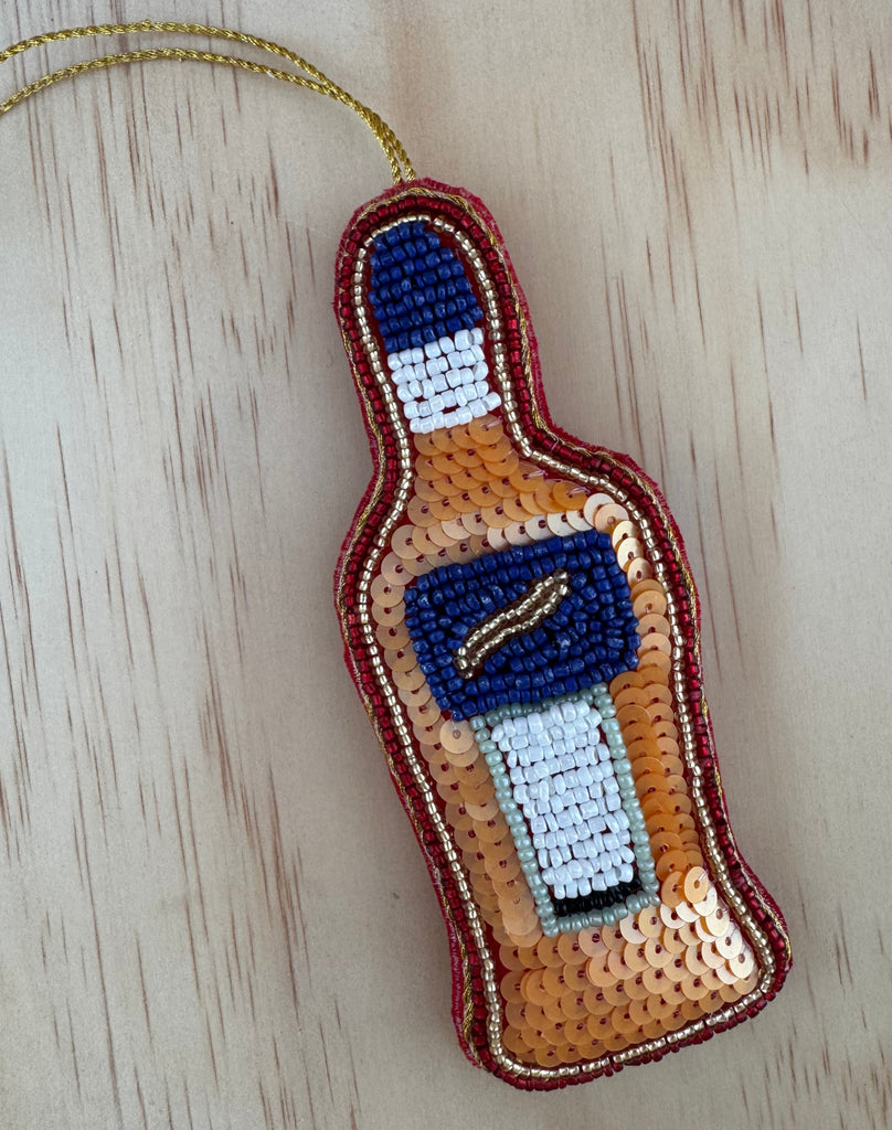 Beaded bottle-shaped object with a label on a wooden surface